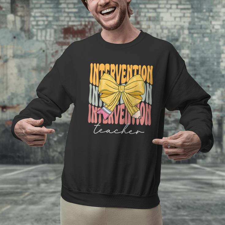 Interventionist Teacher Groovy Coquette Bow Back To School Men Graphic Sweatshirt, Groovy Teacher Sweatshirts, gift for family, gift for coworker