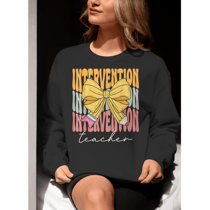 Interventionist Teacher Groovy Coquette Bow Back To School Women Crewneck Sweatshirt, Groovy Teacher Sweatshirts, funny gift
